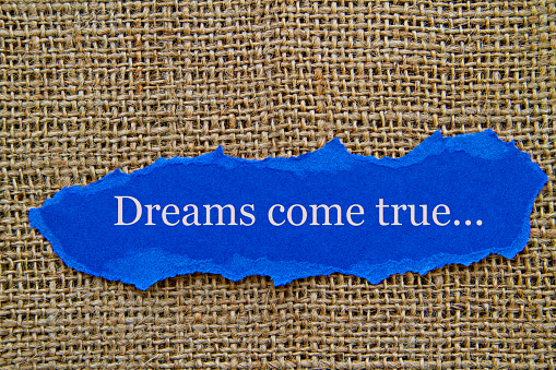 Mentors concept image. Dreams come true word written on torn paper. Burlap background. Role of mentors in UPSC prep